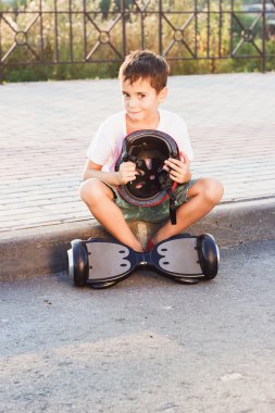 Çocuk bir siyah gyro scooter ile açık havada oturur