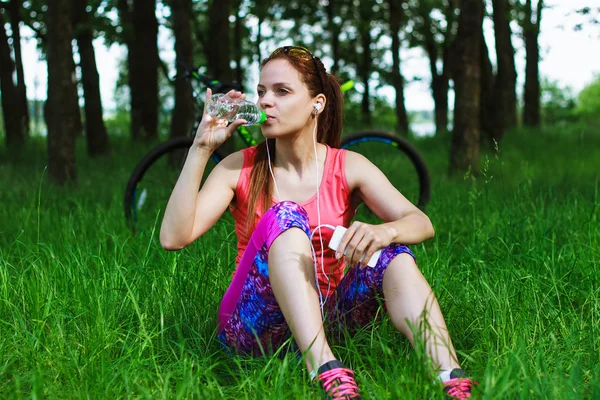 Donna sportiva con una bottiglia d'acqua e un telefono — Foto Stock