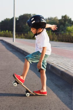 Çocuk bir kaykay ile açık havada duruyor