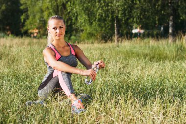 Genç kadın oturur ve yeşil çimenlerin üzerinde dinlenme sahiptir