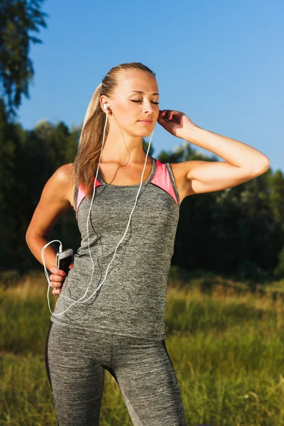 Молодая спортивная и привлекательная женщина слушает музыку Стоковая Картинка