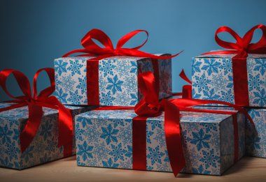 Mavi arka plan üzerinde kırmızı kurdele ile güzel bir paket hediye