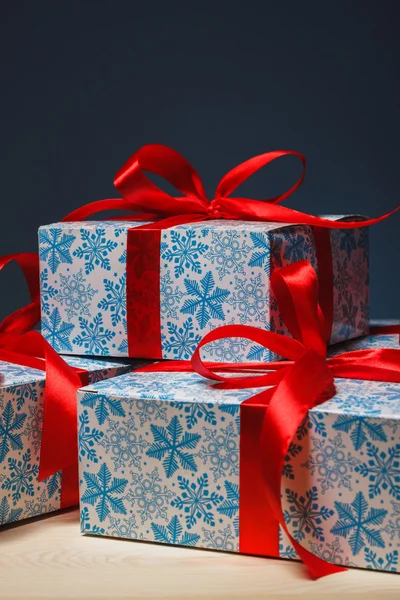 在一个包装精美的蓝色背景上的红丝带的礼物 — 图库照片