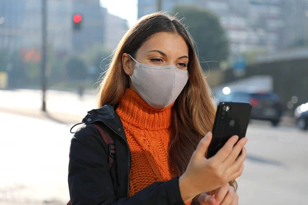 보호용 마스크를 착용하고 휴대폰으로 이메일을 확인하는 사업가 거리에서 택시를 기다리고 — 스톡 사진