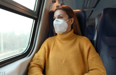 Yeni normal. Sağlık ve güvenlik kurallarına saygı duyarak trende duran koruyucu maskeli yolcular.