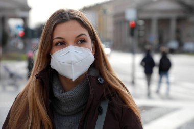 Şaşkınlık hissi var. Kışlık elbiseli, koruyucu maske takan, caddede yürüyen genç bir bayanı yakından çek. Yüzü maskeli kız salgın sırasında kendini yalnız hissediyor.