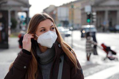 FFP2 KN95 koruyucu maske takan güzel bir kadının kışın açık havada giydiği kıyafetlere baktığı yakın plan.