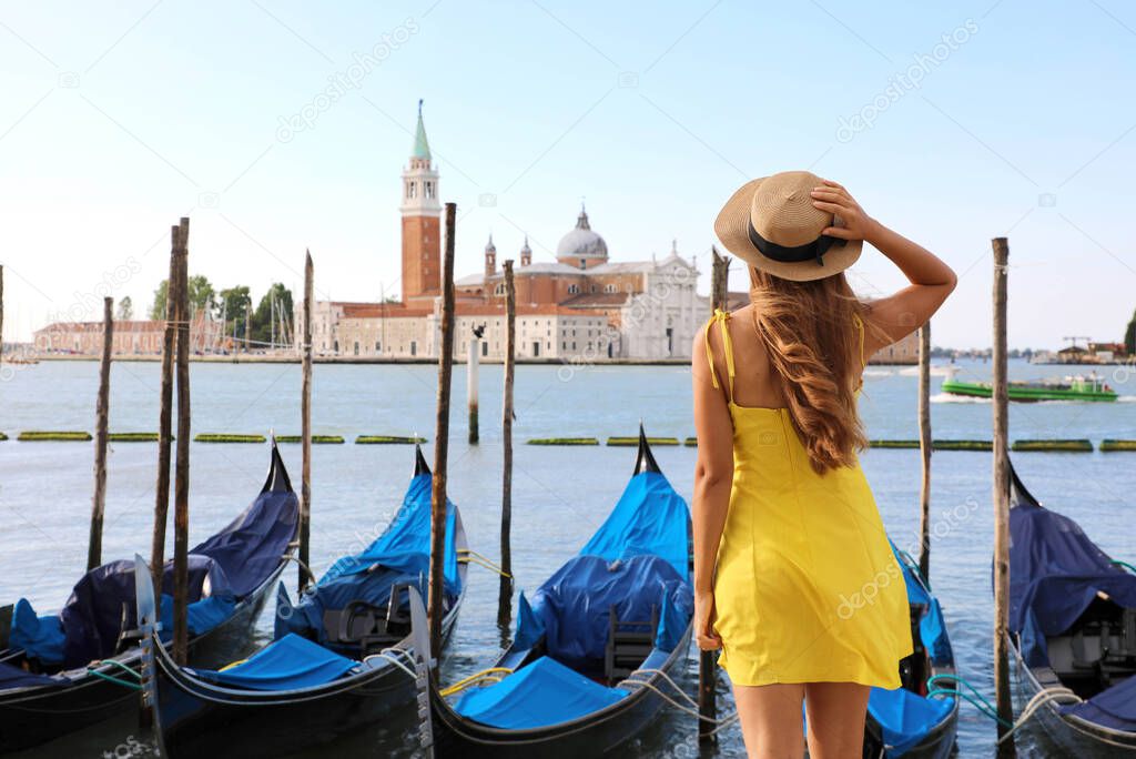 Young female traveler enjoying beautiful view on venetian channel with gondolas floating in Venice, Italy