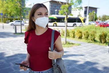 Caddede FFP2 KN95 maskesi takan genç bir kadın.