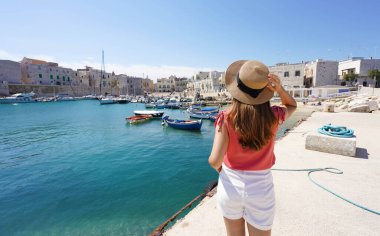İtalya 'yı ziyaret et. İtalya 'nın Apulia kentindeki Giovinazzo limanına bakan genç bayan turistin arka manzarası..