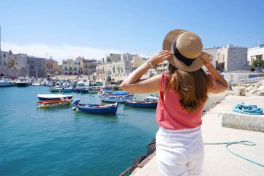 Apulia 'da tatil. İtalya 'nın Apulia kentindeki Giovinazzo Picturesque Limanı' na bakan şapkalı turist kızı..