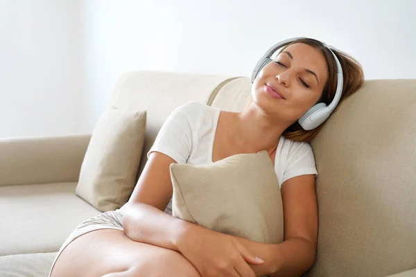 Relaxed Young Woman Headphones Listening Music While Hugs Pillow Napping — Zdjęcie stockowe