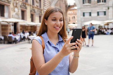 Mavi gömlekli genç bir kadın video görüşmesi için telefon kullanıyor. Kız İtalya Verona 'da akıllı telefonuyla kendi portresini çekiyor..