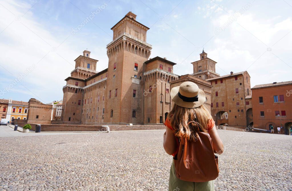 Travel in Italy. Rear view of traveler girl walking towards Este Castle (Castello Estense) of Ferrara, Italy.