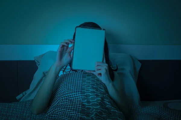 Travail de femme avec tablette ou ordinateur sur le lit la nuit — Photo