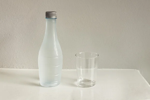 Üveg víz és pohár a fehér asztal — Stock Fotó