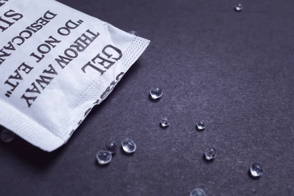 Close-up van silica gel of droogmiddel in papieren zak op zwarte pagina — Stockfoto