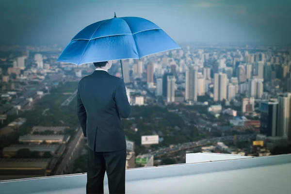 Обратный вид бизнесмена с зонтиком на крыше и взглядом — стоковое фото