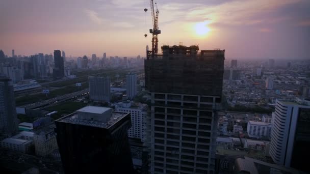 Vue aérienne du dessus à la construction de la grue de travail et de la zone de la ville au coucher du soleil crépusculaire, inclinaison vers le haut, HD de haute qualité — Video