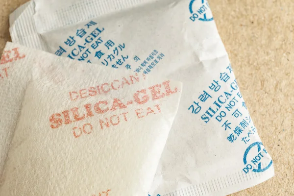 Close-up van silica gel of dessicant, niet-Engelse tekst te vertalen naar "Silicagel eet niet" in papieren zak achtergrond — Stockfoto