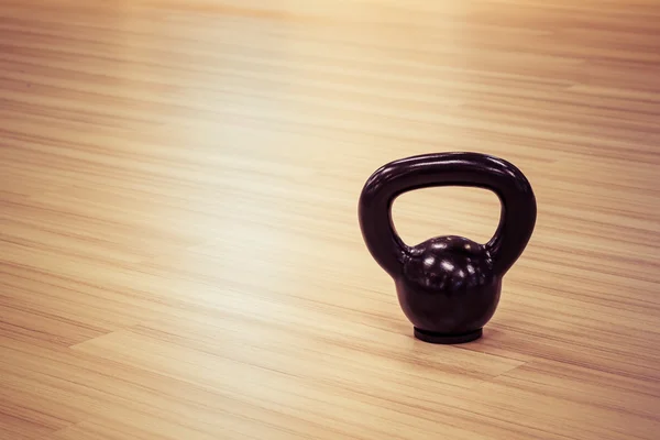 Ferro preto kettlebell peso no chão de madeira — Fotografia de Stock