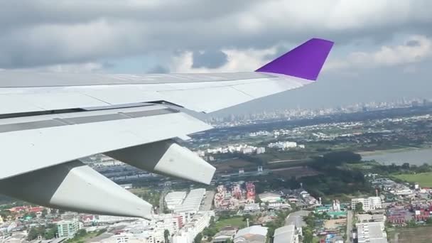 Wing of an airplane flying above the town or city. shot from the window of the plane — Stock Video