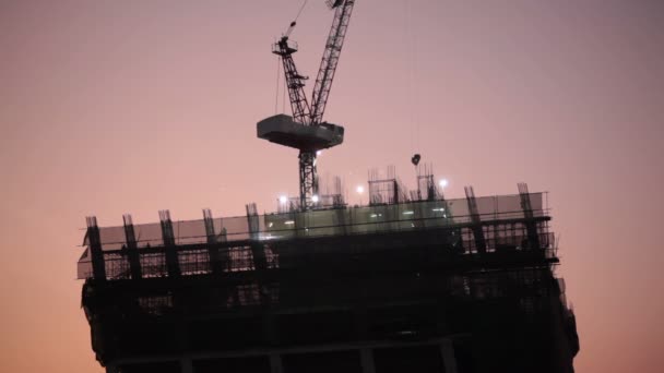 Bauarbeiter auf Industriebaustelle, Bauentwicklung für Wolkenkratzer, aufgenommen bei Sonnenuntergang, Tiefblick — Stockvideo