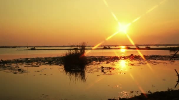 Puesta de sol con resplandor en forma de estrella de fondo, en el río o lago y casa de inundación en el suelo en el crepúsculo, cámara panorámica disparo — Vídeo de stock