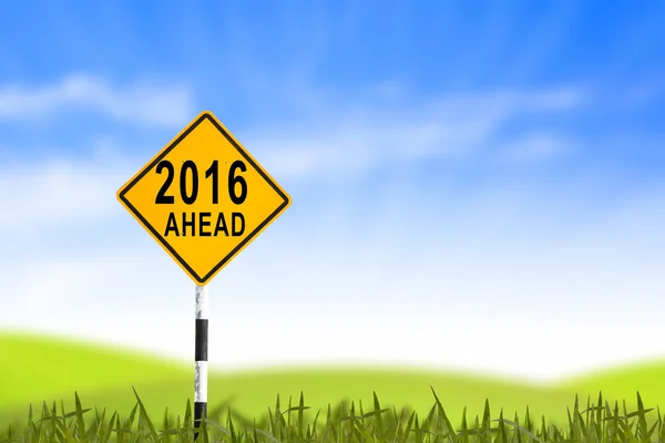 2016, Road sign in the grass field to new year and blue sky, can — Stockfoto