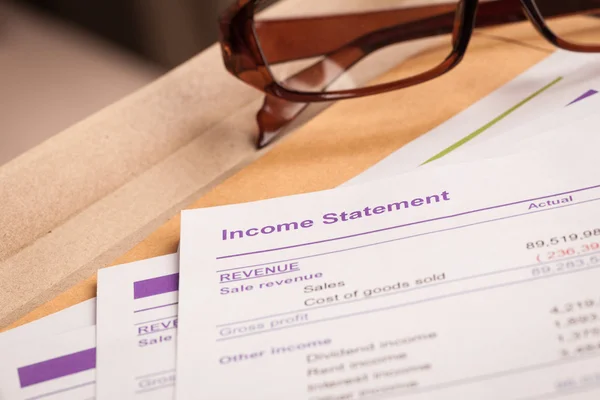 Income statement letter on brown envelope and eyeglass, business — Stock Photo, Image