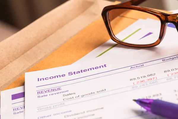 Inkomst uttalande brev på bruna kuvert och glasögon, penna, bu — Stockfoto