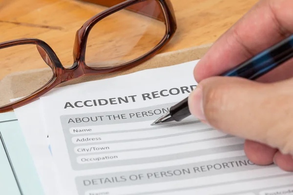 Accident report application form and human hand with pen on brow — Stock Photo, Image