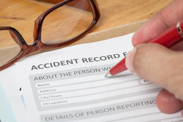 Accident report application form and human hand with pen on brow — Stock Photo, Image
