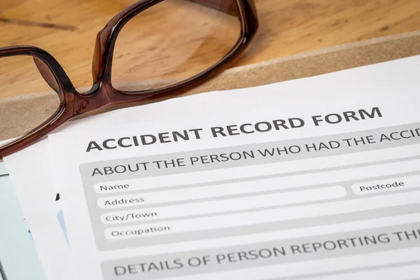 Accident report application form on brown envelope and eyeglass, — Stock Photo, Image