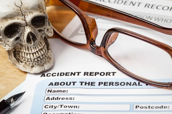 Ongeval verslag aanvraagformulier en menselijke schedel op bruine envelo — Stockfoto