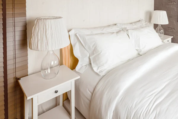 Dwie poduszki na sypialnię z białe prześcieradło i lampa — Zdjęcie stockowe