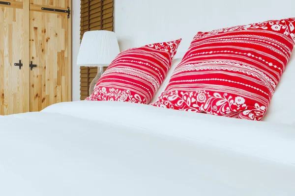Červený polštář na ložnici s bílým prostěradlem a svítilnou — Stock fotografie