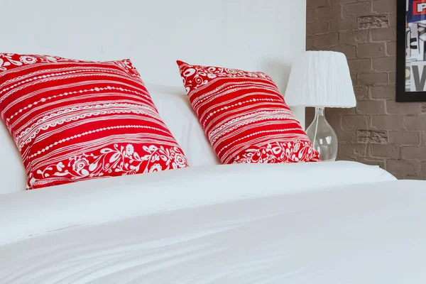 Red pillow on bedroom with white bed sheet and lamp — Stock Photo, Image