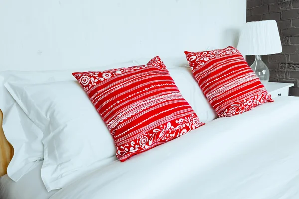 Red pillow on bedroom with white bed sheet and lamp — Stock Photo, Image