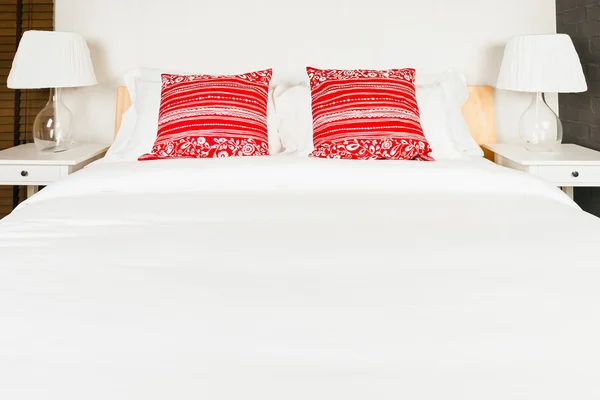 Red pillow on bedroom with white bed sheet and lamp — Stock Photo, Image