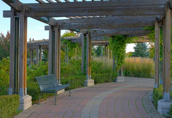 Bench under under a shaded arbor in Toronto park. Stock Picture