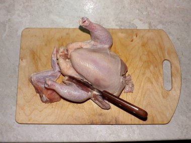 Bir tavuk leşini doğramak. Kesme tahtasında çiğ tavuk eti.