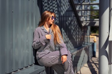 Parapedi üzerine çömelmiş bir kadın yan tarafa bakıyor.