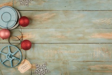 Ahşap arka planda kırmızı noel baloları ve sinema objeleri