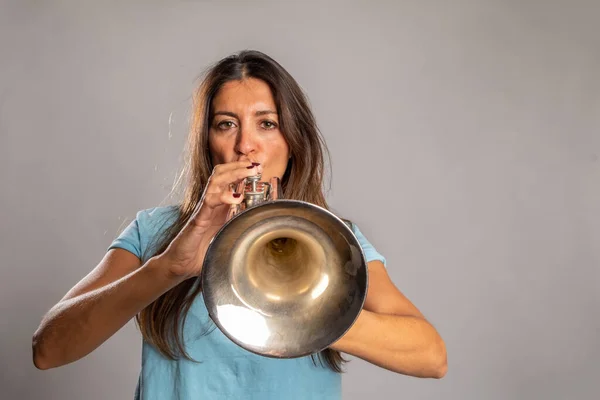 woman playing trumpet on a gray background