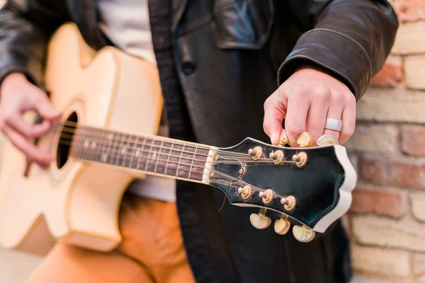 Uliczny muzyk zamyka gitarę. Palce obracające kołki strojenia gitary akustycznej — Zdjęcie stockowe