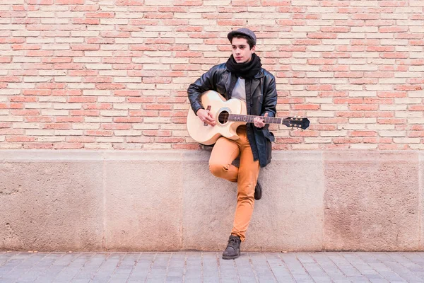 Músico de rua tocando guitarra acústica. Jovem homem de mão vestindo casaco e chapéu ao ar livre — Fotografia de Stock