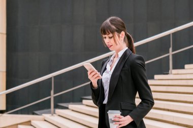 İşe giderken akıllı telefon kullanan güzel bir iş kadınının portresi.