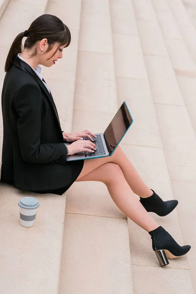 Портрет красивой деловой женщины с помощью ноутбука, сидящего на лестнице на городской улице. — стоковое фото