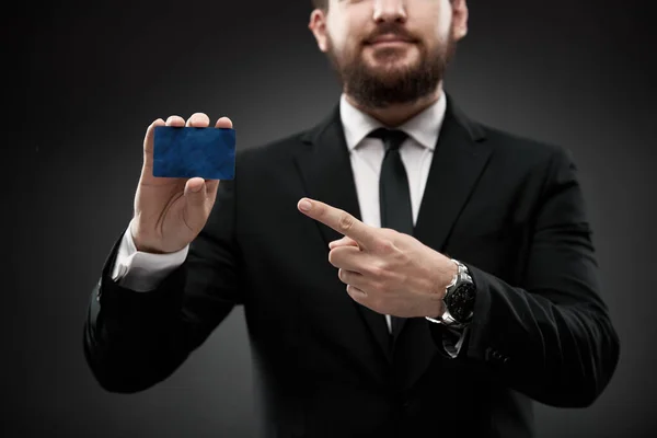 Close up of man in suit holding and pointing to credit card.